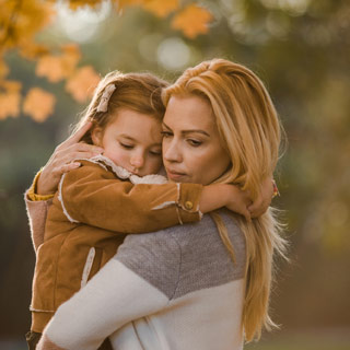 Little girl clings to her mom in a moment of separation anxiety.