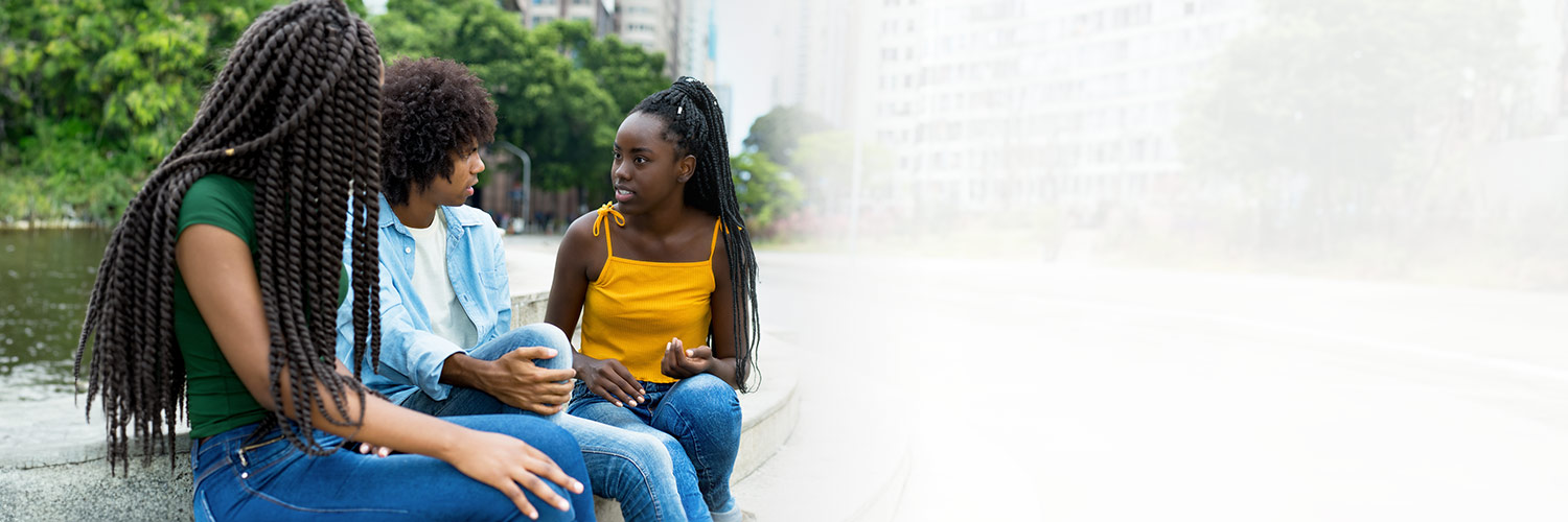 Three teenagers sitting on steps outside talking.