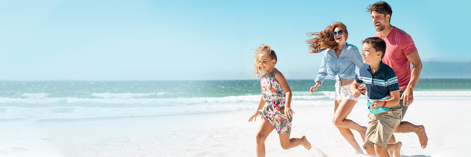 A family running together on the beach.