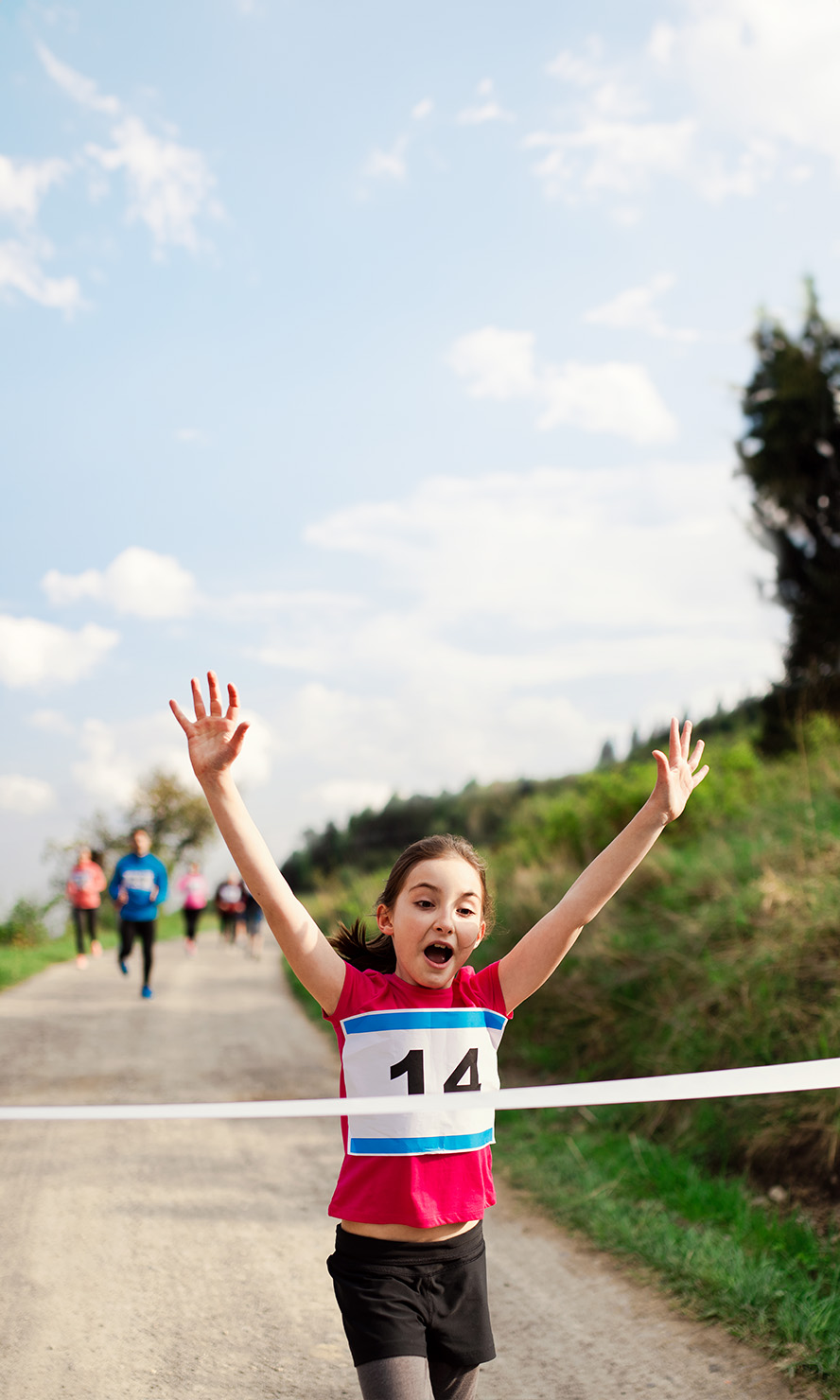 Young girl running through the finish line at a race.