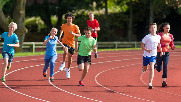 Group of school children running on track.