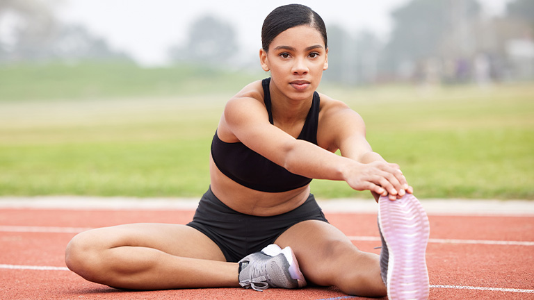 Teenage girl stretching before a track and field event.