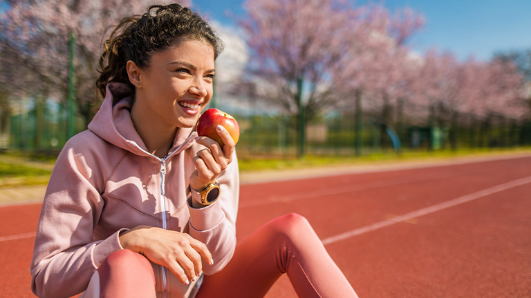 Young girl eating an apple on the school track.